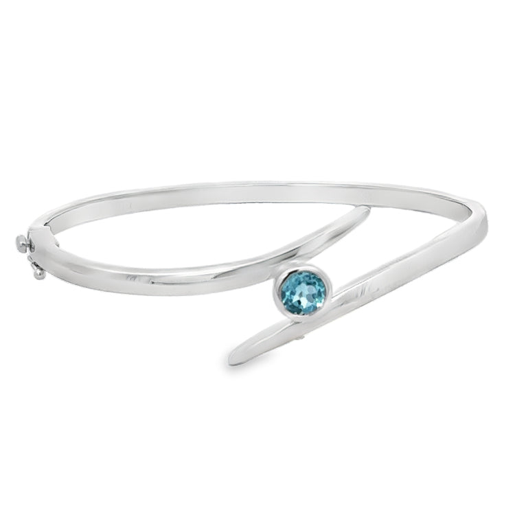 Sterling Silver Hinged Bangle Bracelet with bezel set genuine Blue Topaz in a bypass design. Fastens with a pressure clasp and supplemental safety-8.&amp;nbsp;