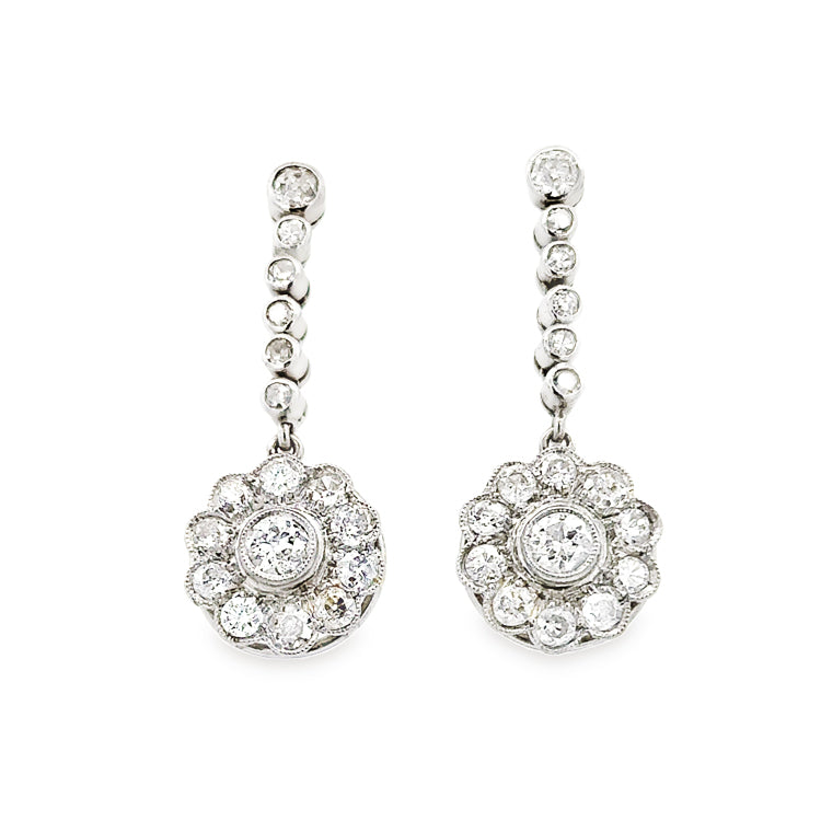 Estate platinum Art Deco earrings with approximately 1.5TW diamonds, SI1-SI2 clarity and G-H color. The design features a line of five, bezel-set diamonds that drop from a slightly larger bezel-set diamond stud. A floral cluster of ten diamonds surrounding a larger center diamond dangles from the bezel-set diamonds.  Dimensions; 1-1/8&quot; long, 1/2&quot; diameter cluster