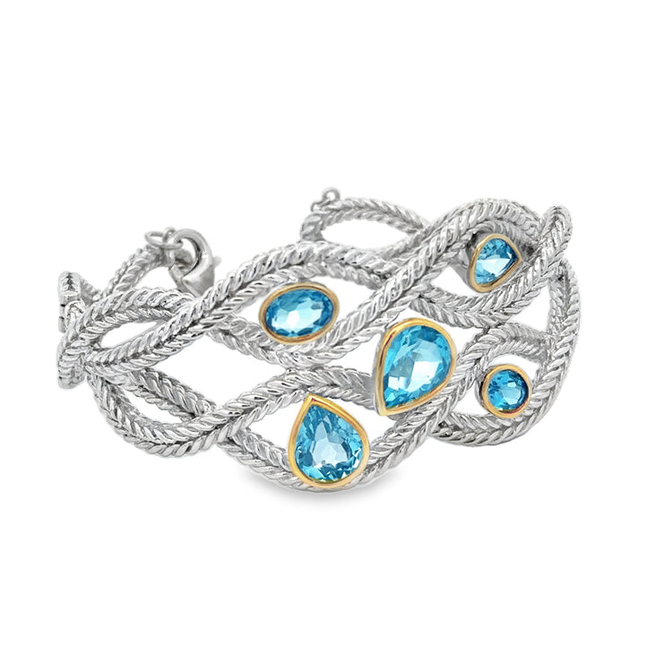 Sterling Silver open weave design cuff bracelet with Oval and Pear shape Blue Topaz in 14Kt yellow gold bezels. Solid craftsmanship with a hinge on one side for easy on and off. Safety chain with lobster clasp.